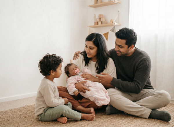 Toddler Meeting New Baby Through Role Play | Nurtura Australia Toddler sitting with parents and a realistic baby doll, representing a new sibling introduction through gentle role play