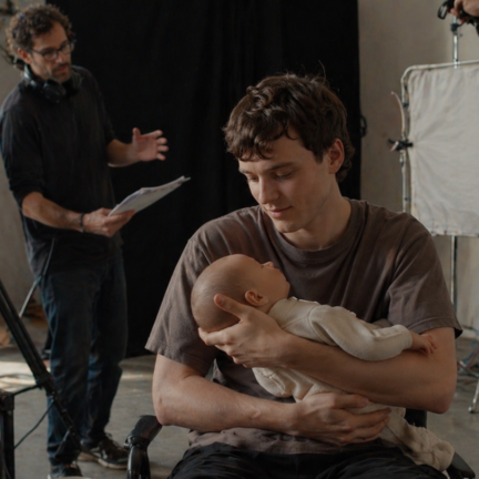 Actor holding a realistic silicone baby doll on a film set during production