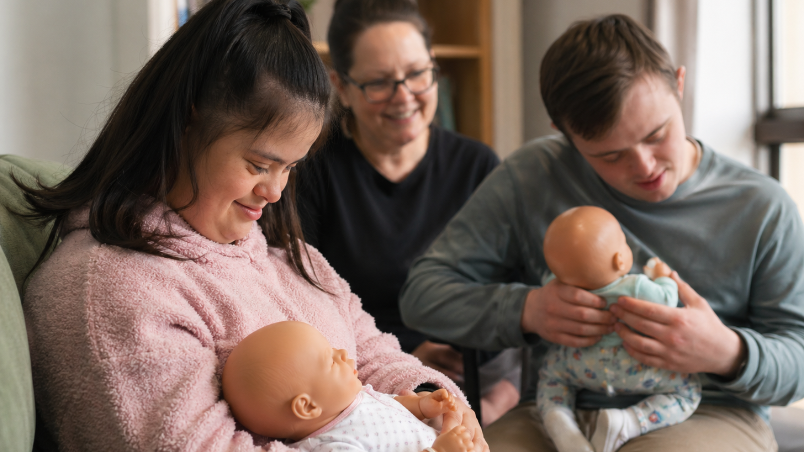 Young adults in a supported setting gently interacting with realistic silicone baby dolls during a guided NDIS support session.